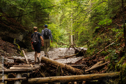 Two friends are traveling through the mountains in the summer with backpacks. In the mountain forest.