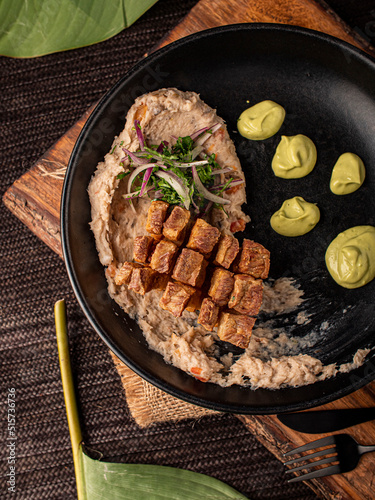 Chicharrón sobre cama de frijol refrito