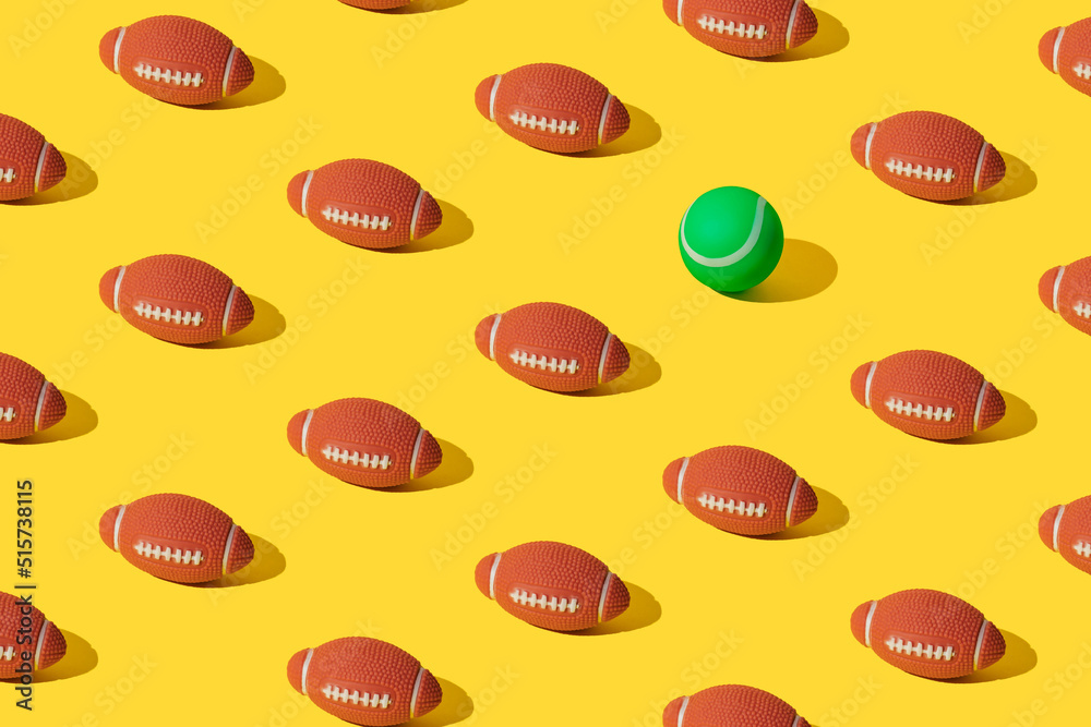 Arranged rugby balls on a yellow background with on green tennis ball.