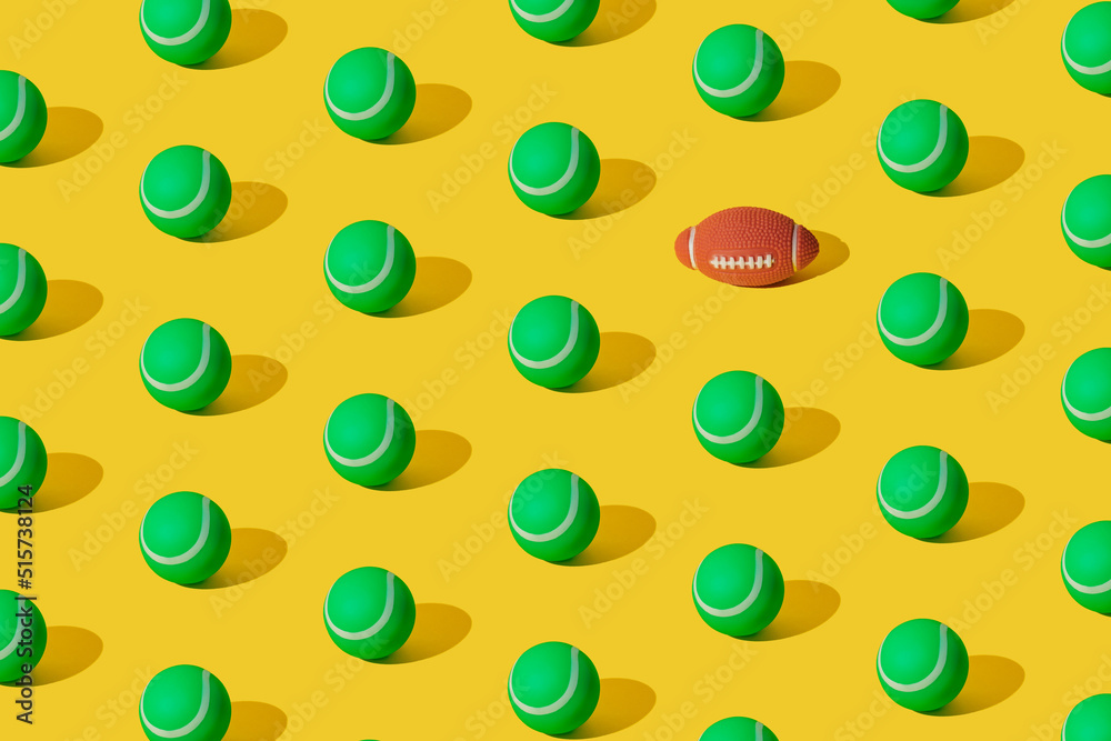 Arranged of green rubber tennis balls and one rugby ball on yellow pastel background. Pattern. Arranged of green rubber tennis balls and one rugby ball on yellow pastel background. Pattern.