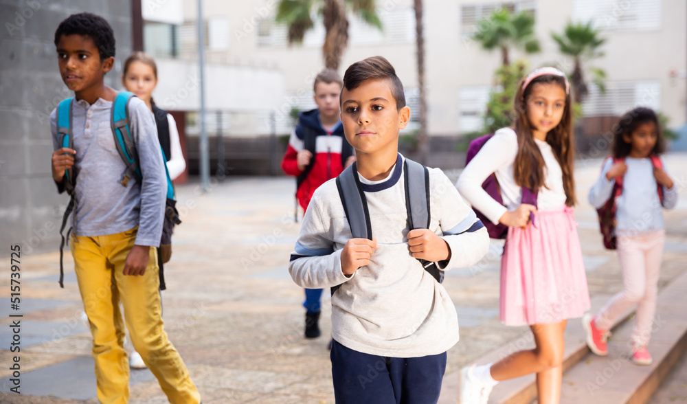 Obraz premium Portrait of preteen Hispanic boy with rucksack walking outdoors on his way to school on warm autumn day. Back to school concept.