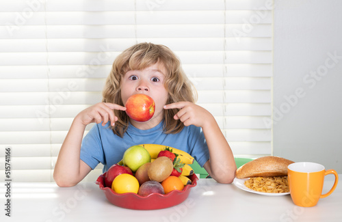 Funny child eating apple. Kid preteen boy 7, 8, 9 years old eating healthy food vegetables. Breakfast with milk, fruits and vegetables. Child eating during lunch or dinner at home.