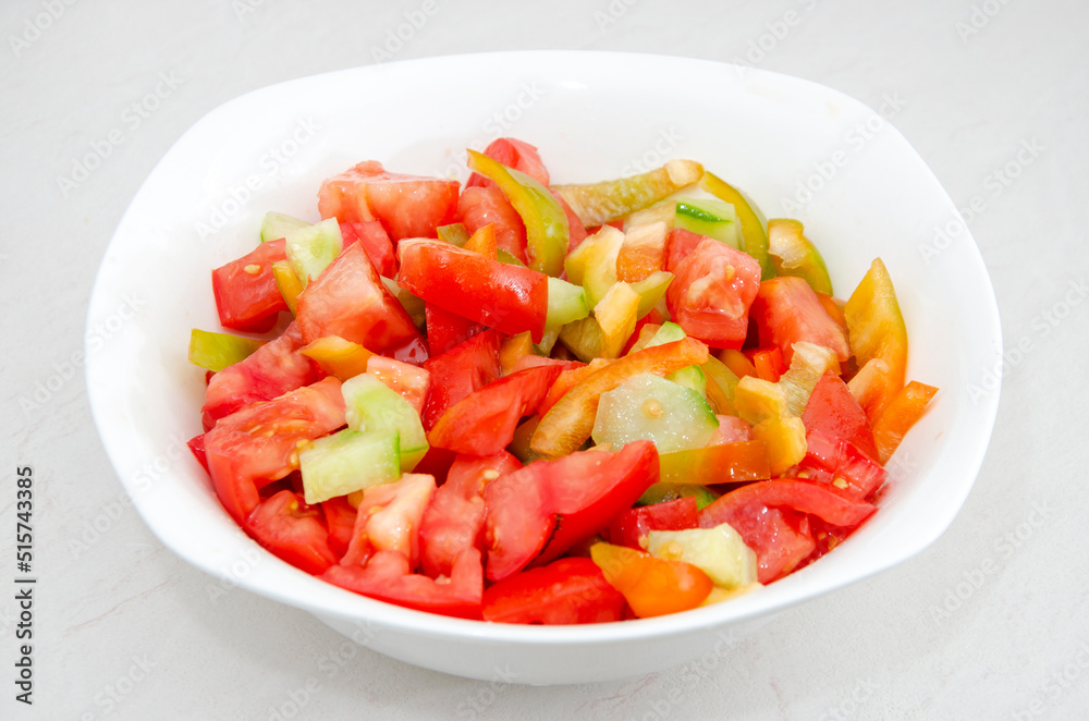 White plate with fresh tomato and sweet pepper salad. Close-up