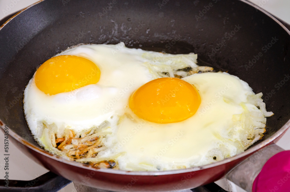 Fried eggs with onions in a pan. Close-up Fried eggs with onions in a pan. Close-up