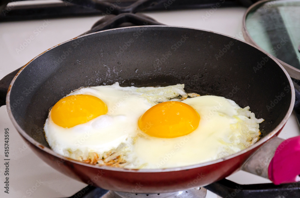 Fried eggs with onions in a pan. Close-up