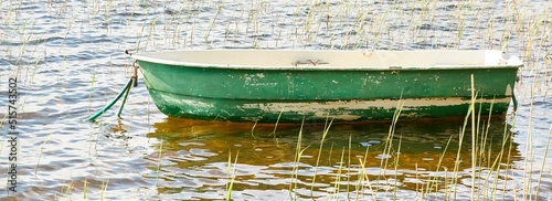 Small green boat anchored in forest lake. Scandinavia. Transportation, traditional craft, recreation, leisure activity, healthy lifestyle, local tourism, sport, rowing, hiking, summer vacations themes