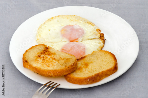 Fried eggs and slices of toasted bread on a white plate. Close-up