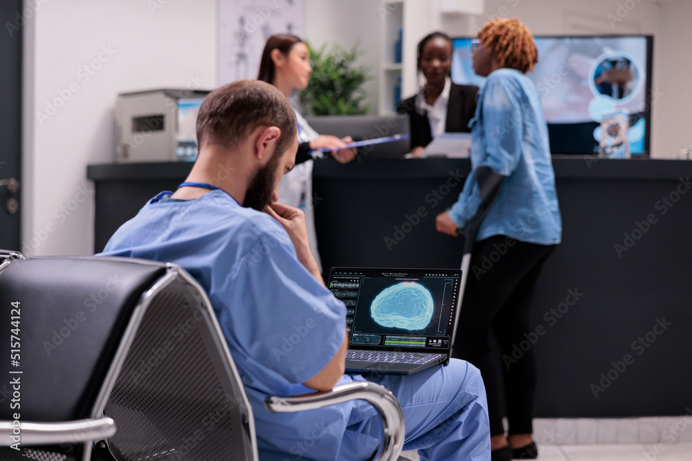 Medical assistant analyzing brain animation on laptop, sitting in waiting room hospital lobby. Looking at neurology illustration of vital organ on computer display at healthcare clinic.