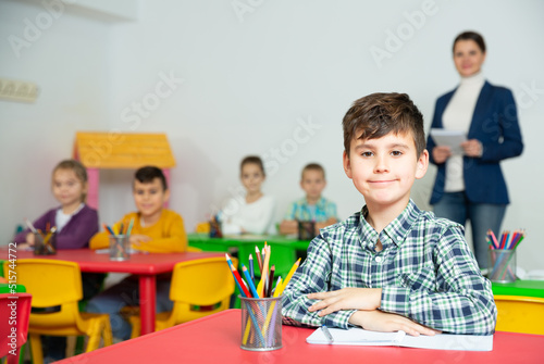 Preteen boy studying in classroom on background with classmates and teacher. High quality photo