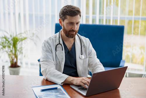 Doctor therapist with stethoscope using laptop while working at medicine office