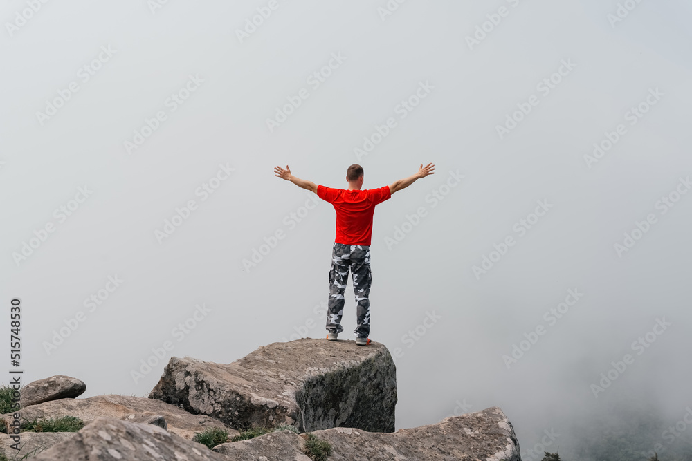 Hiker man on the top of the mountain enjoys the aerial view, raising his hands above the clouds. Mount Pidan Hiker man on the top of the mountain enjoys the aerial view, raising his hands above the clouds. Mount Pidan