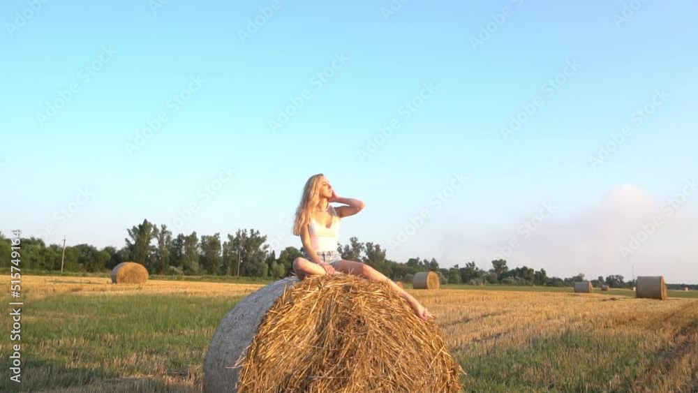Slow Motion a girl is sitting on a haystack in a field Slow Motion a girl is sitting on a haystack in a field