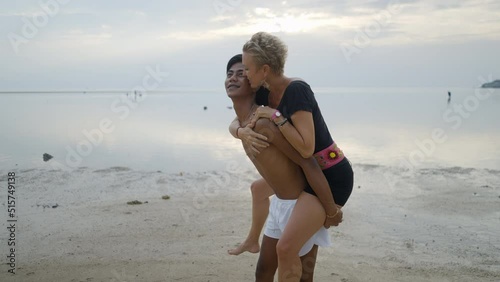 Lovely Interracial couple piggyback ride and kissing at the beach at sunset
