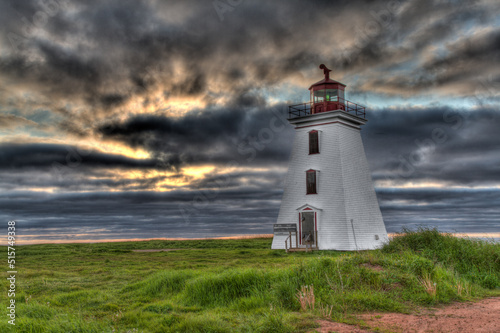 lighthouse in grass with clouds at sunset