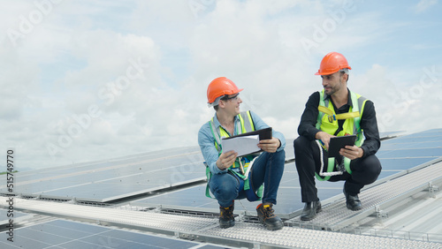 Engineer and construction worker examining solar panels on rooftop.
