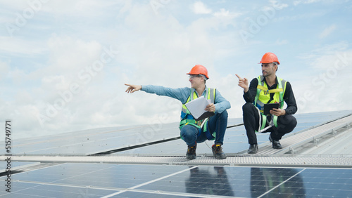 Engineer and construction worker examining solar panels on rooftop.