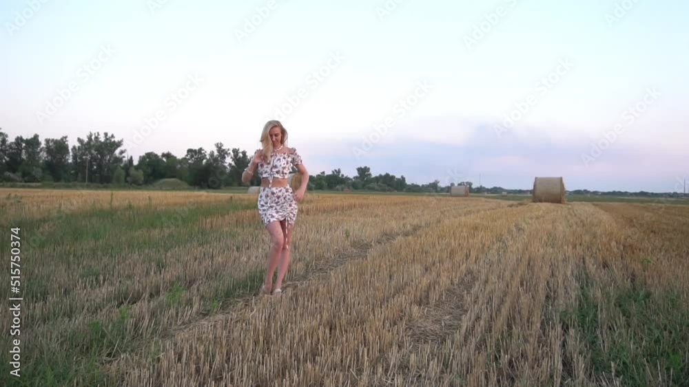 Young woman walking on a field sunset time Young woman walking on a field sunset time