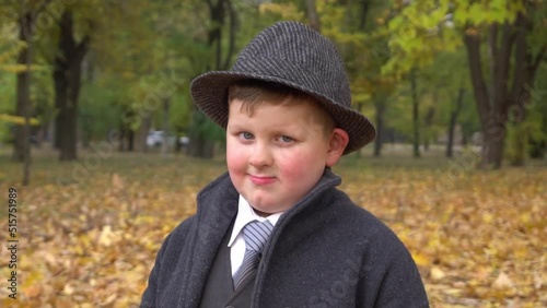 Slow Motion Small child in a business suit in autumn park photo