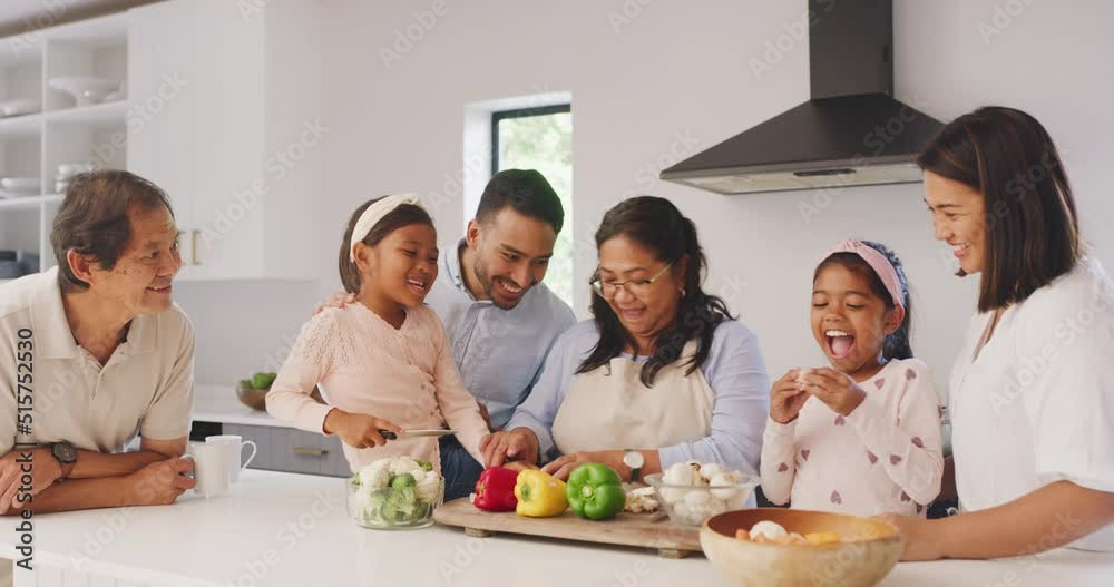 Happy multi generation family cooking together in the kitchen. Asian kids, parents and grandparents chopping vegetables and preparing a healthy meal at home. Having fun and spending time together