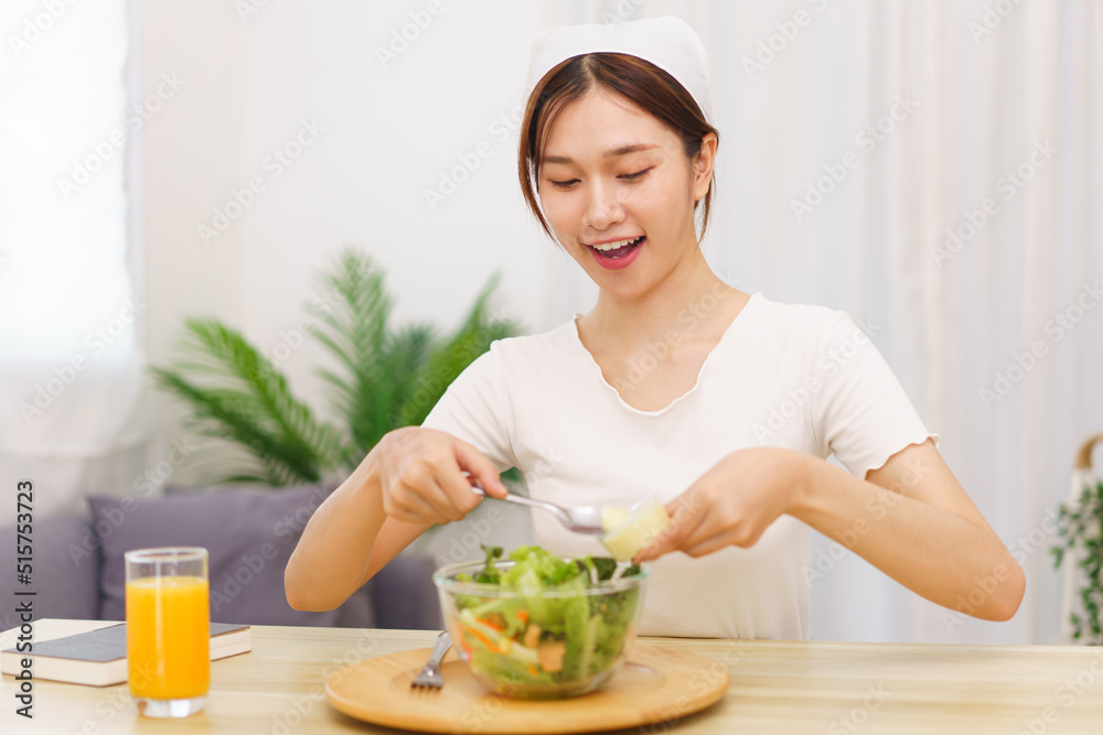 Lifestyle in living room concept, Asian woman using spoon to ladle salad dressing into salad bowl Lifestyle in living room concept, Asian woman using spoon to ladle salad dressing into salad bowl