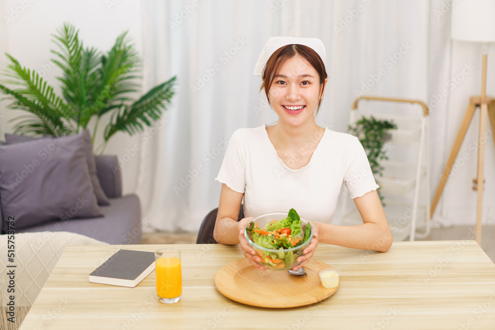 Lifestyle in living room concept, Young Asian woman smiling and holding bowl of vegetable salad Lifestyle in living room concept, Young Asian woman smiling and holding bowl of vegetable salad