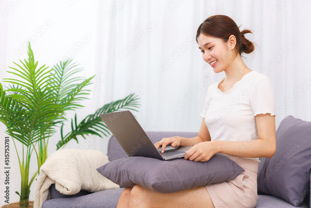 Lifestyle in living room concept, Asian woman sit on couch and using laptop to surfing social media Lifestyle in living room concept, Asian woman sit on couch and using laptop to surfing social media