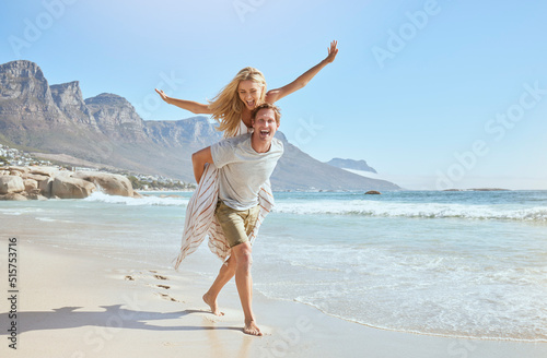 Portrait of a happy and loving young couple enjoying a day at beach in summer. Cheerful affectionate husband giving his joyful wife a piggyback while walking and having fun by the seashore on holiday