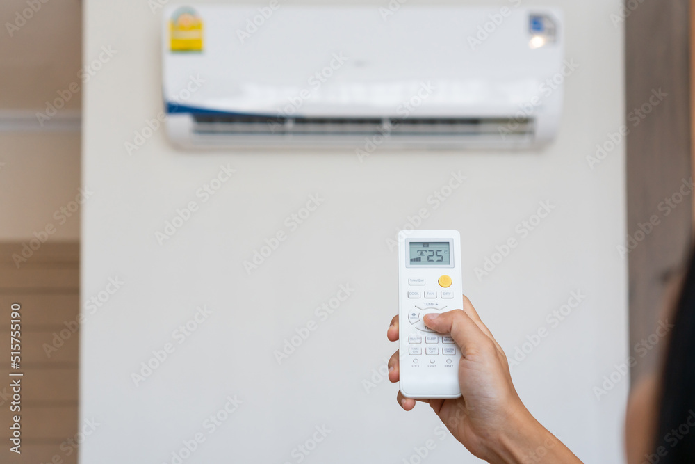 Asian woman hand adjust air conditioner to 25 degrees celsius with remote control. Health concepts and energy savings