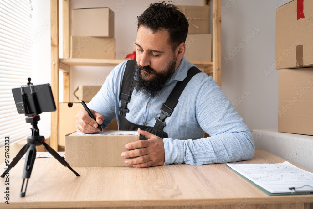 Start up. Indian man have new order from customer using mobile phone and delivery parcel box on table, small business owner working at home office, SME, shopping online Start up. Indian man have new order from customer using mobile phone and delivery parcel box on table, small business owner working at home office, SME, shopping online