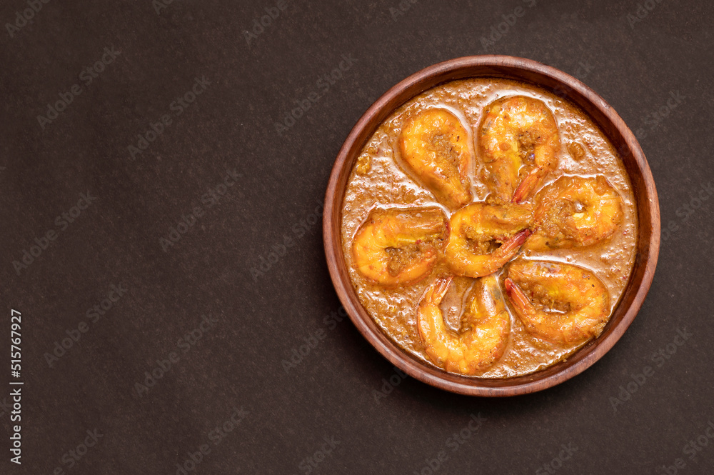 Bengali Dish or Food - Delicious authentic Bengali Prawn Malai Curry also known as chingri malai curry served on a wooden bowl. Traditional Goan Prawns or Shrimp curry. top view black background Bengali Dish or Food - Delicious authentic Bengali Prawn Malai Curry also known as chingri malai curry served on a wooden bowl. Traditional Goan Prawns or Shrimp curry. top view black background
