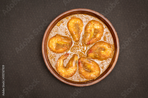Bengali Dish or Food - Delicious authentic Bengali Prawn Malai Curry also known as chingri malai curry served on a wooden bowl. Traditional Goan Prawns or Shrimp curry. top view black background.