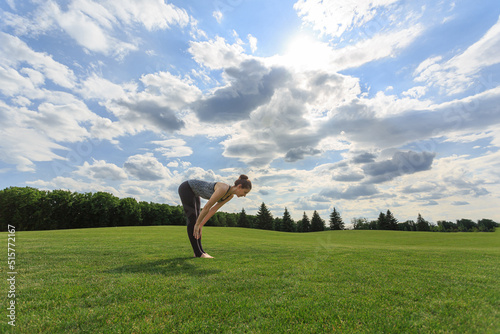 Woman stretching on green grass before yoga or fitness in park
