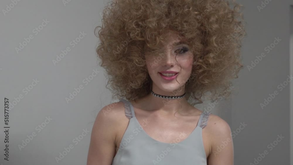 Slow Motion Young woman with beautiful curly hair on gray background Slow Motion Young woman with beautiful curly hair on gray background