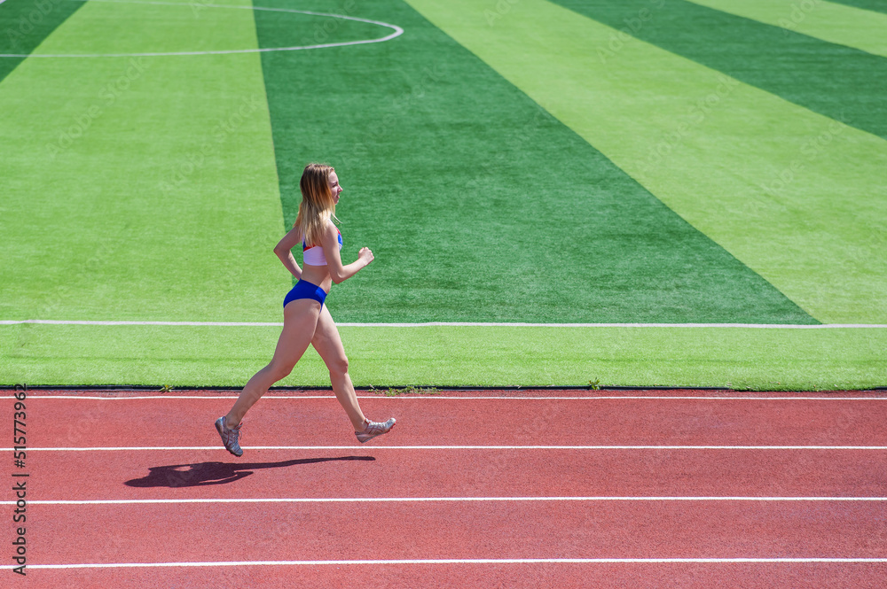Fototapeta premium Young caucasian woman is engaged in jogging at the stadium outdoors.
