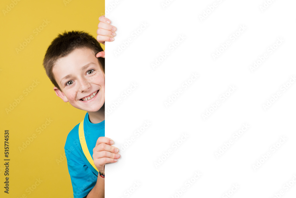 Cheerful boy hidden behind white billboard with copy space. Cheerful boy hidden behind white billboard with copy space.