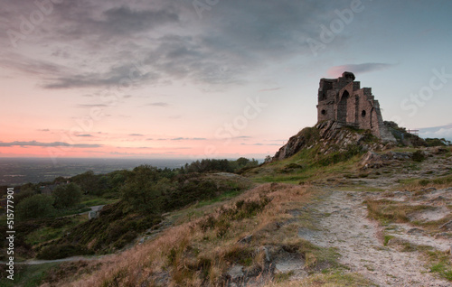 Mow Cop Castle  Cheshire   Staffordshire  England in sunlight with blue sky  clouds and distant landscape  landscape format.