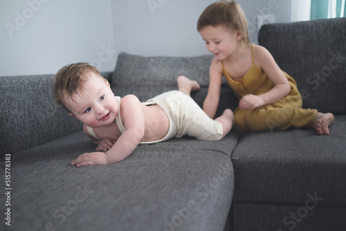 Sibling children play on sofa in living room together