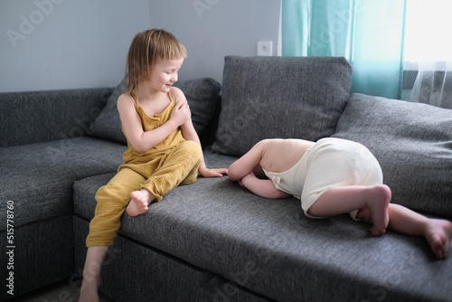 Sibling children play on sofa in living room together