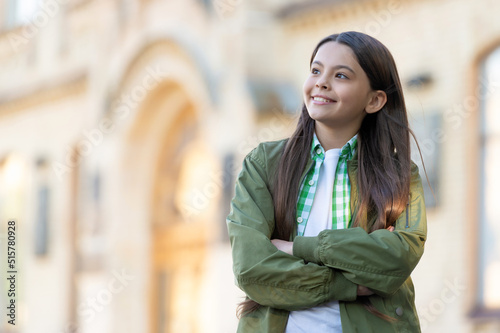 Happy teenage girl keeping arms crossed outdoors, copy space