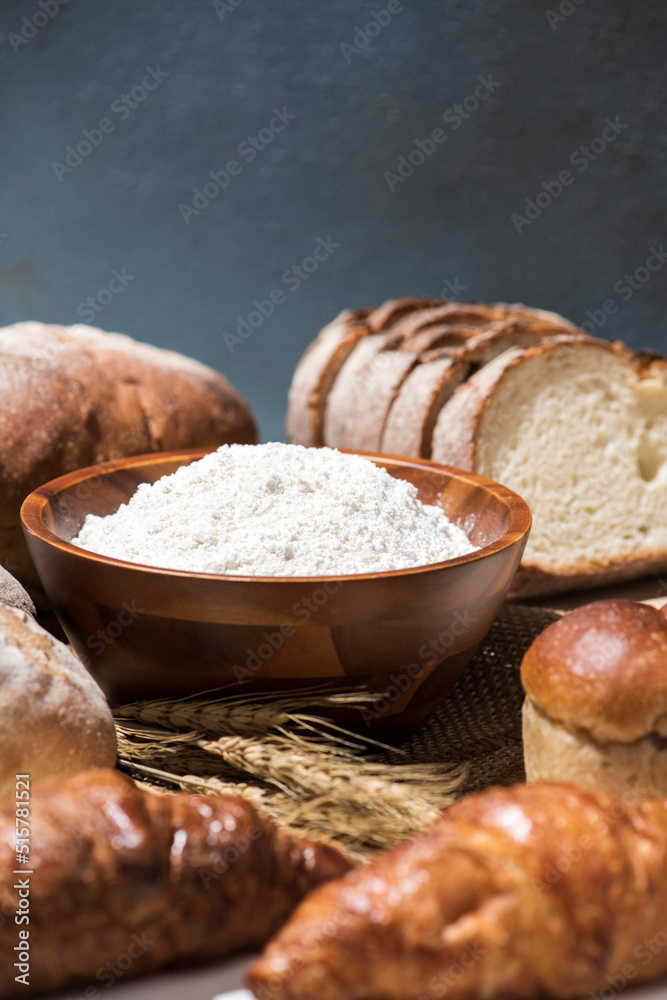 Fototapeta premium テーブルに並んだたくさんの種類のパンと小麦粉