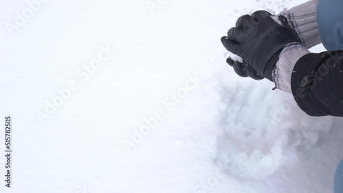 Man makes a snowman at winter day. Winter activities, fun