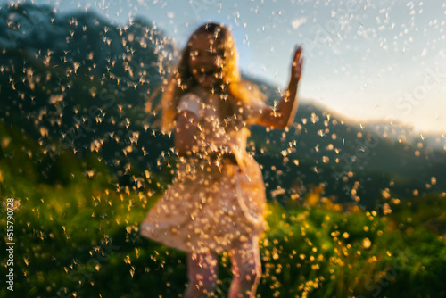 Out of focus girl dancing against the background of a flying dandelion in the mountains