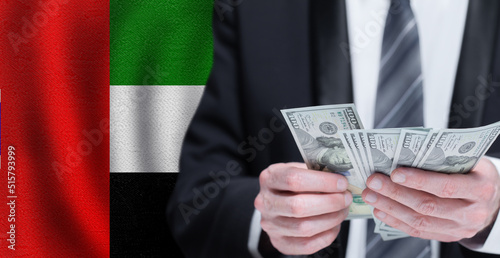 Hands holding dollar money on flag of United Arab Emirates