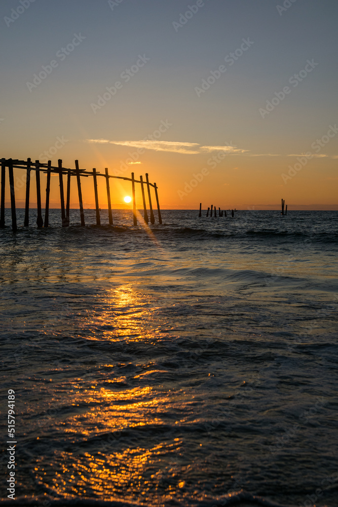 Sunrise through a fishing pier at the beach