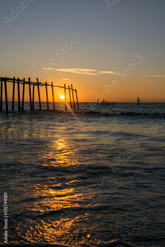 Sunrise through a fishing pier at the beach