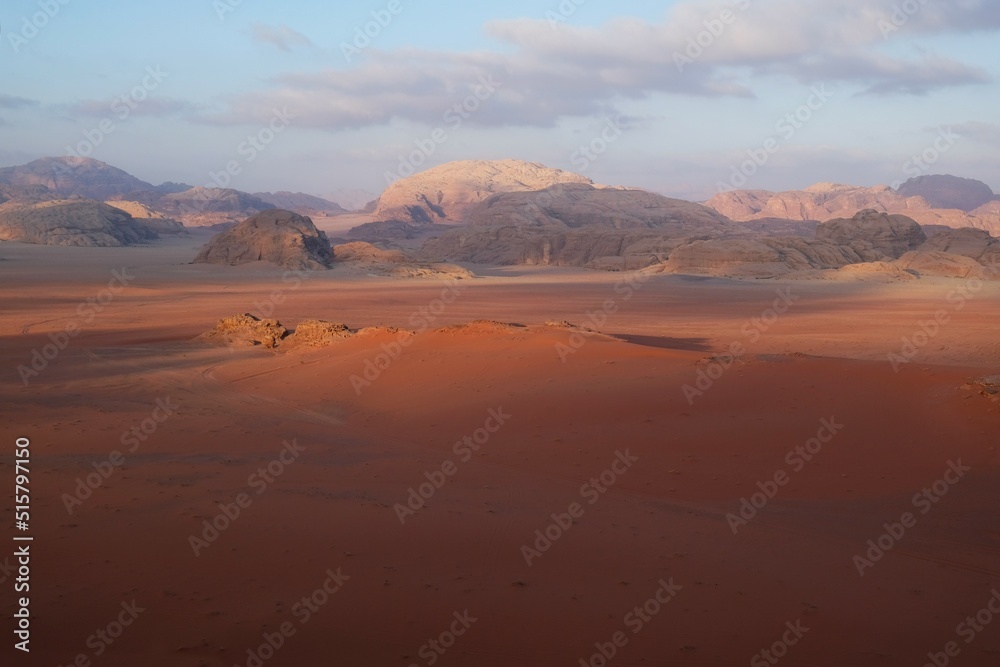 Amazing scenery of Wadi Rum desert with red dunas at sunrise. Desert looks like Mars. Jabal Al Qatar mountain on horizon.