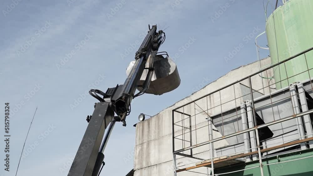 Huge black bucket, grabs sand and moves it to a large sand hangar. Black bucket grabs sand and moves it to concrete kneading tank at production site Huge black bucket, grabs sand and moves it to a large sand hangar. Black bucket grabs sand and moves it to concrete kneading tank at production site