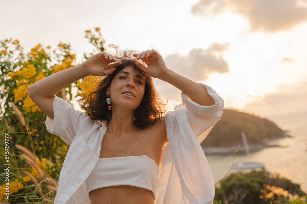 Tender young caucasian model girl poses looking at camera outdoors. Brunette with bob haircut wears white top and shirt. Summer vacation concept. Tender young caucasian model girl poses looking at camera outdoors. Brunette with bob haircut wears white top and shirt. Summer vacation concept.