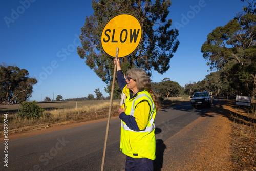 mature lady with slow and stop sign managing traffic on road
