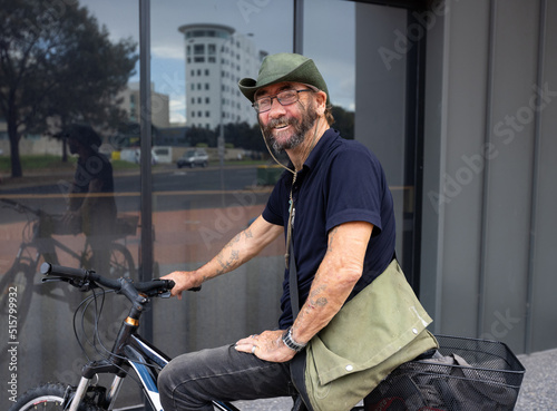 unkempt man on bicycle with multi-storey apartment building reflected in window photo